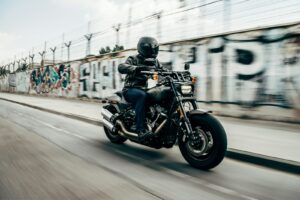 Motociclista con casco in sella alla moto su una strada asfaltata