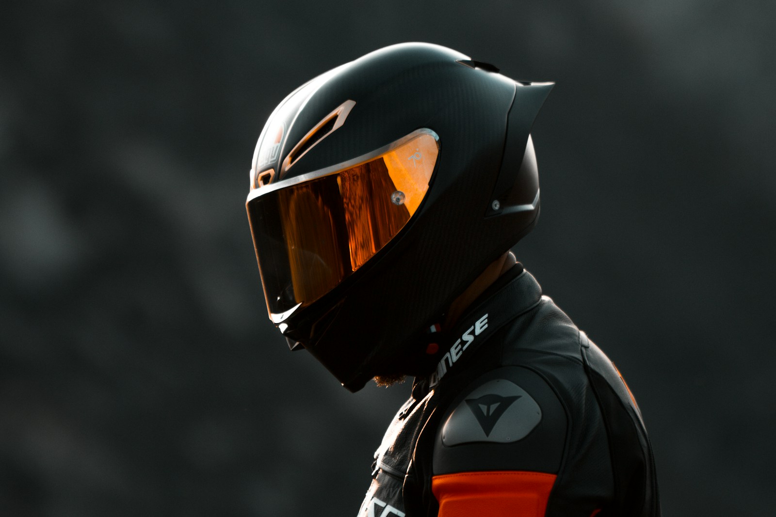 Motociclista di profilo con casco integrale in carbonio opaco e visiera specchiata