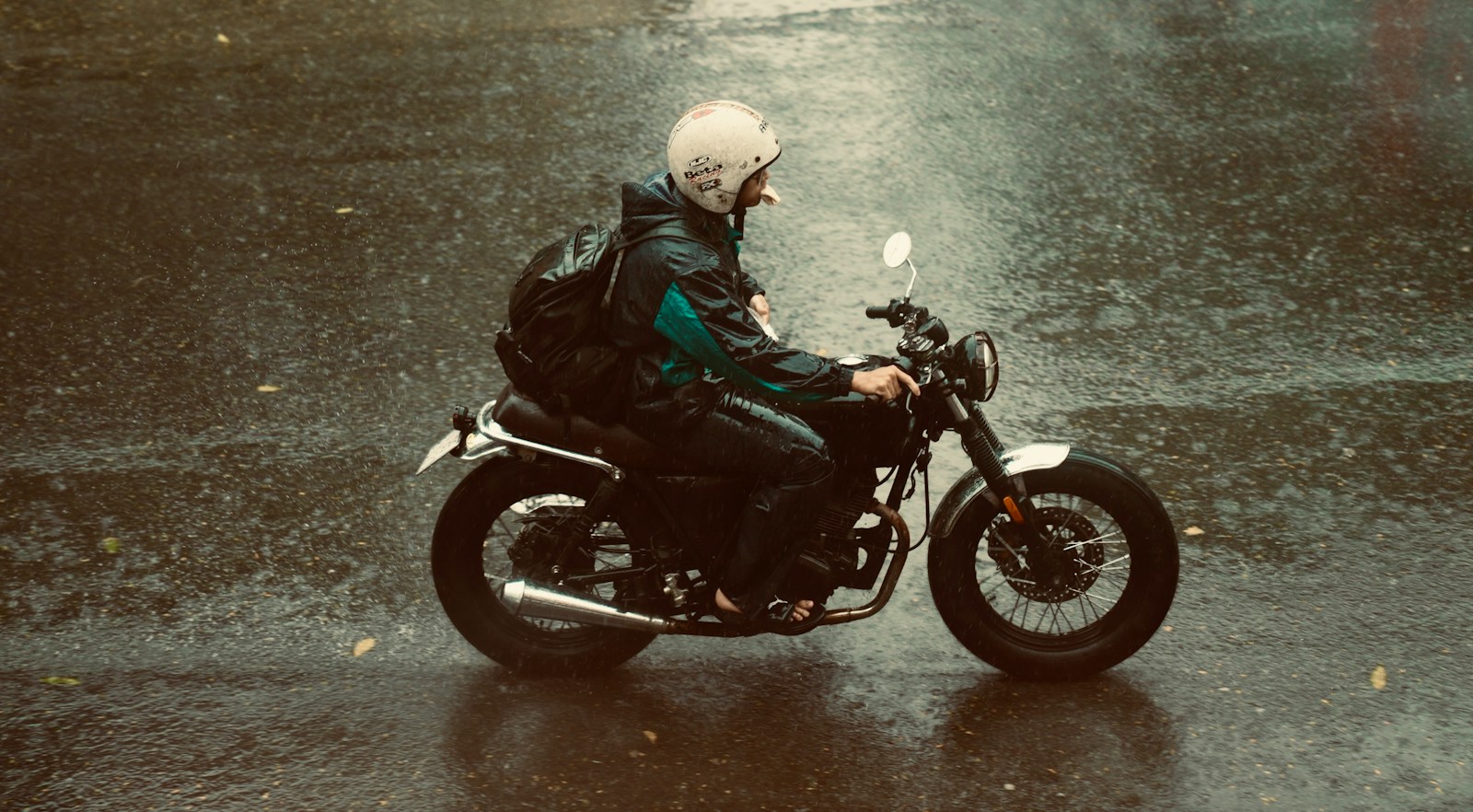 Motociclista in sella su una strada bagnata dalla pioggia