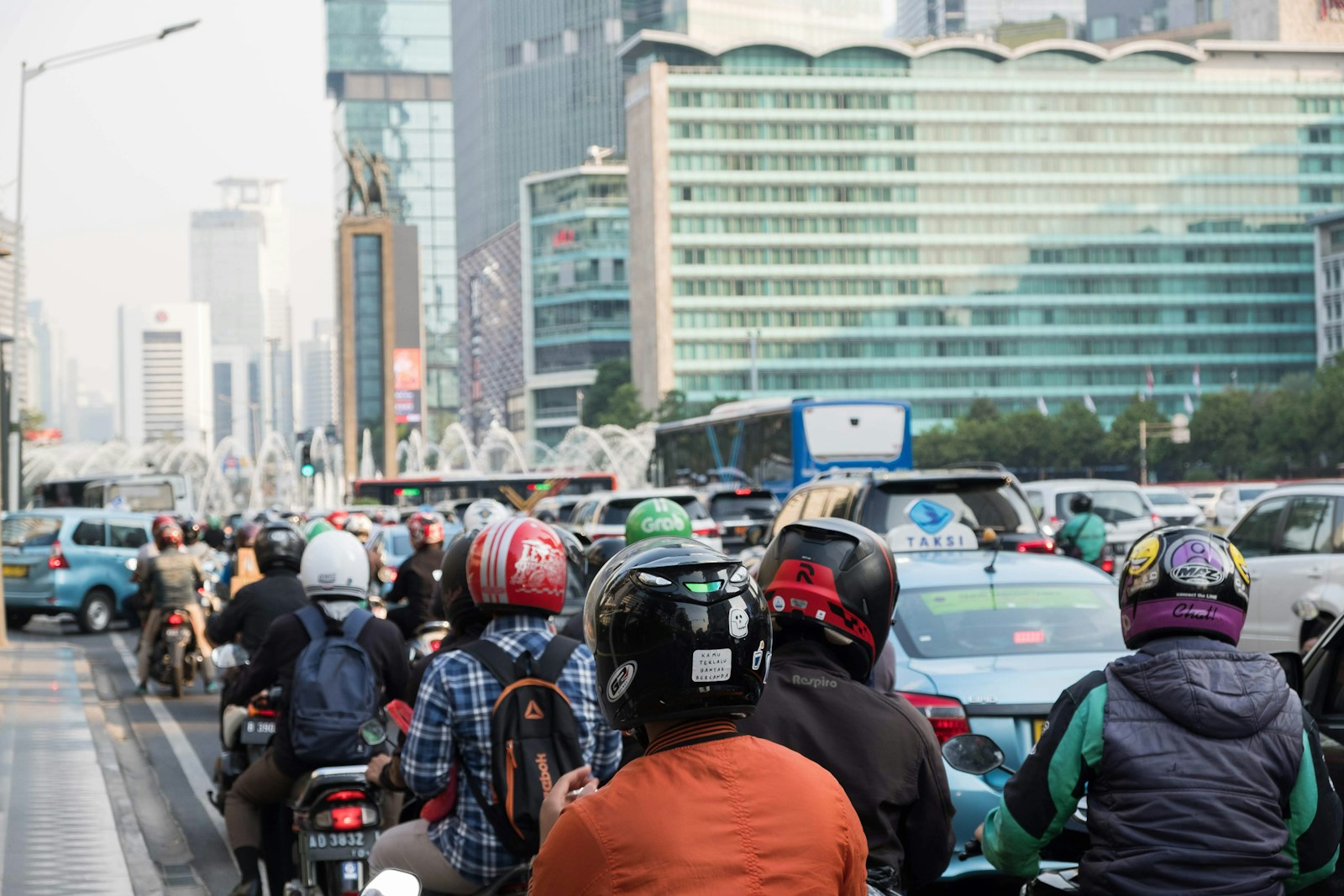 Motociclisti e scooteristi con il casco fermi nel traffico cittadino