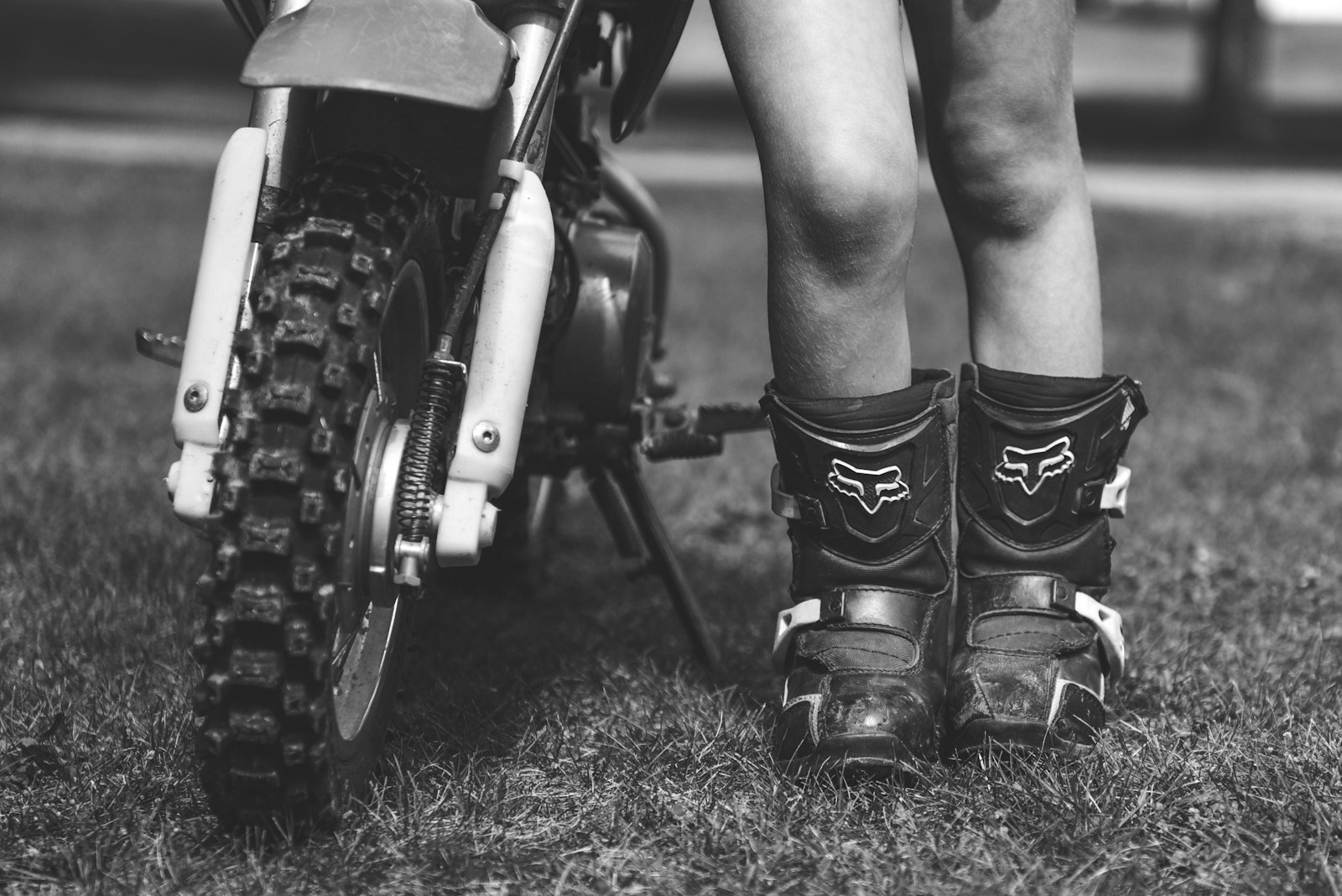 Stivali da moto appoggiati accanto alla ruota di una moto sull'erba