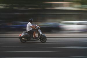 Motociclista in sella a uno scooter in città con il casco jet